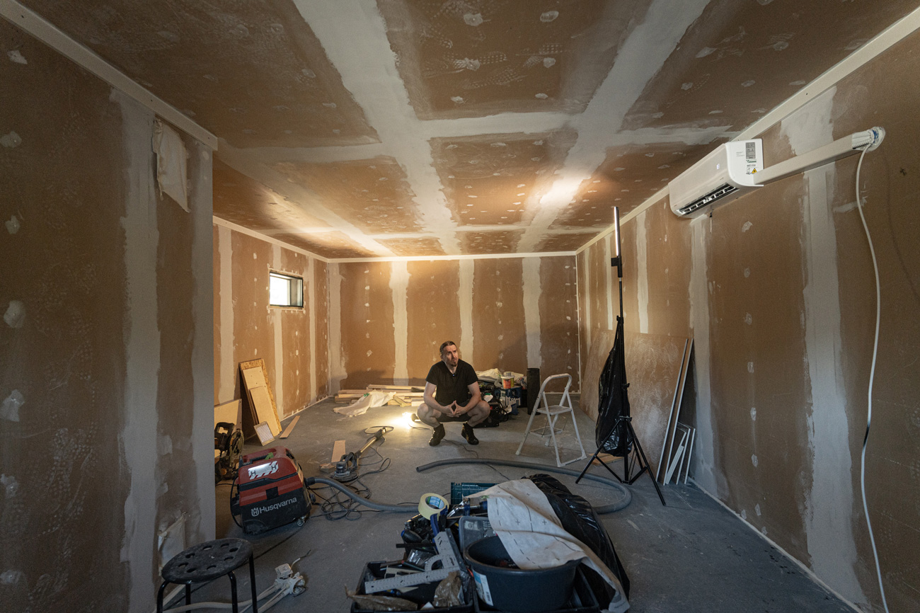 Room-within-a-room framing stage showing the inner wall structure inside the garage with rock wool