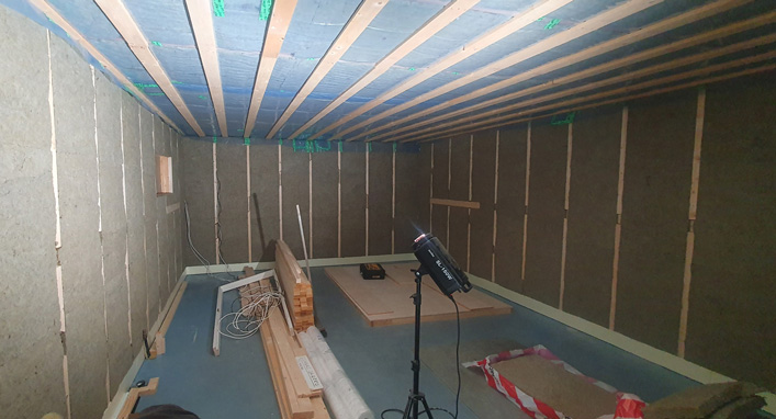 Room-within-a-room framing stage showing the inner wall structure inside the garage with rock wool